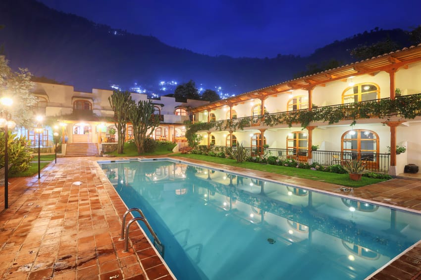 Piscina termal iluminada de noche con montañas