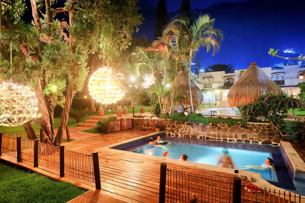 Villa Santa Catarina jardines y piscina iluminados de noche con esferas de luz