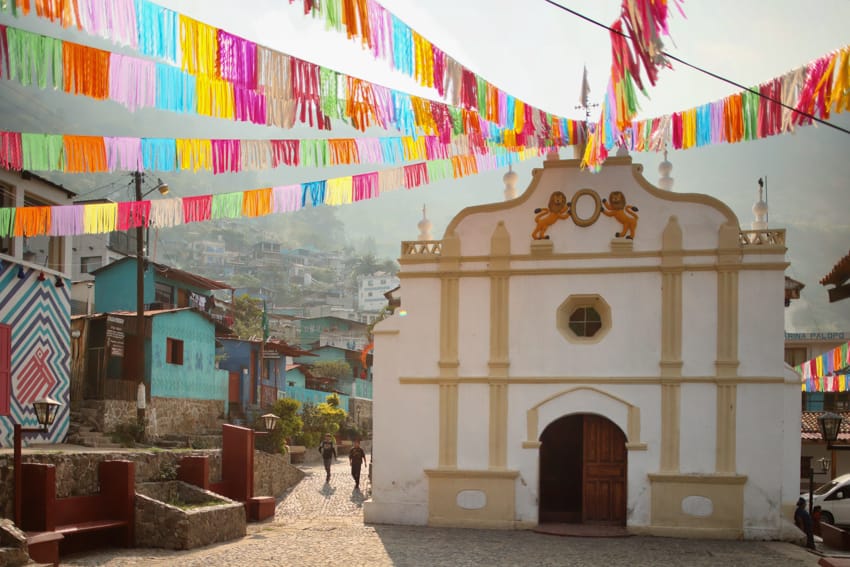 Iglesia de Santa Catarina con banderas coloridas y volcán
