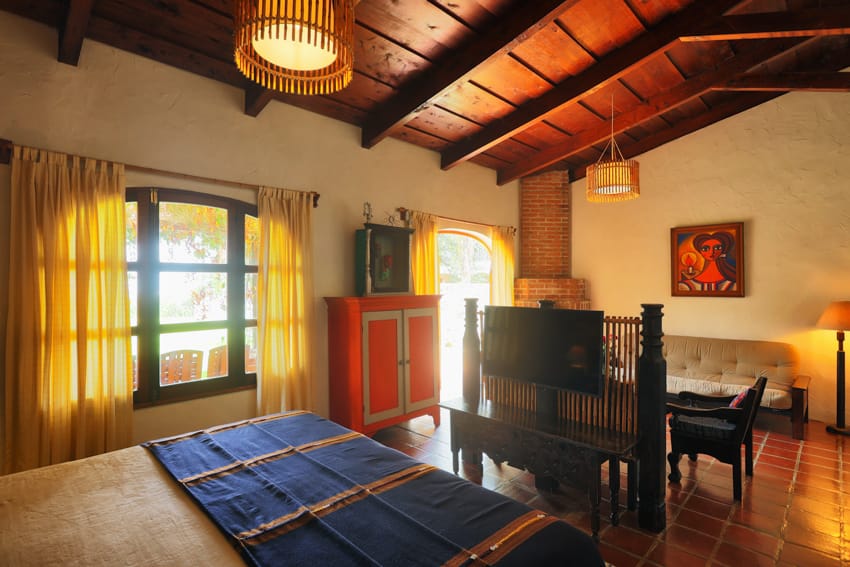 Habitación triple con armario rojo, sillón y techo de madera