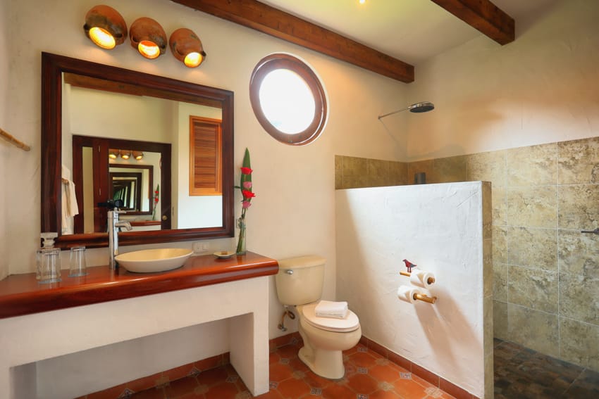 Baño con ducha abierta, ojo de buey, lavamanos de cerámica