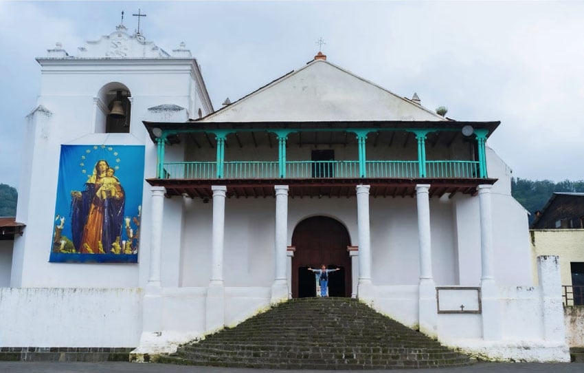 Iglesia colonial blanca con balcón turquesa y virgen