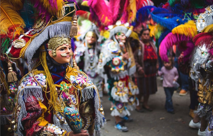 Danzantes con máscaras y plumas en fiesta patronal